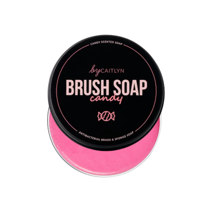 Pink brush soap in a container with black lid on a white background